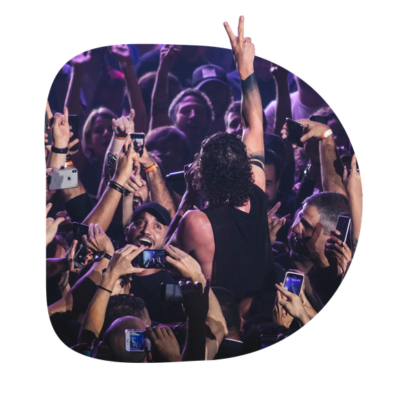 A crowd at a live concert filming and cheering for a performer on stage