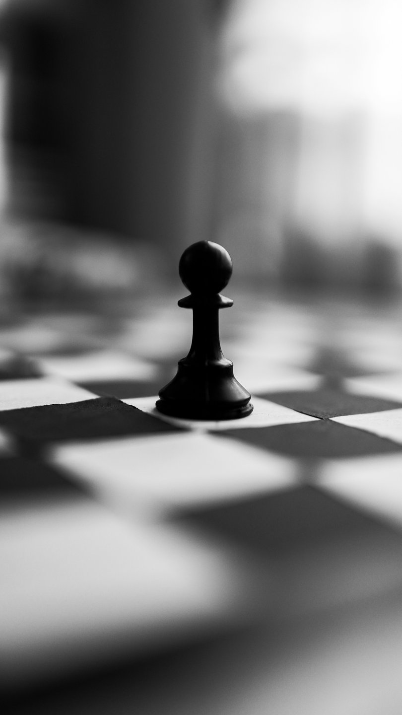 A single chess pawn standing alone on a checkered board